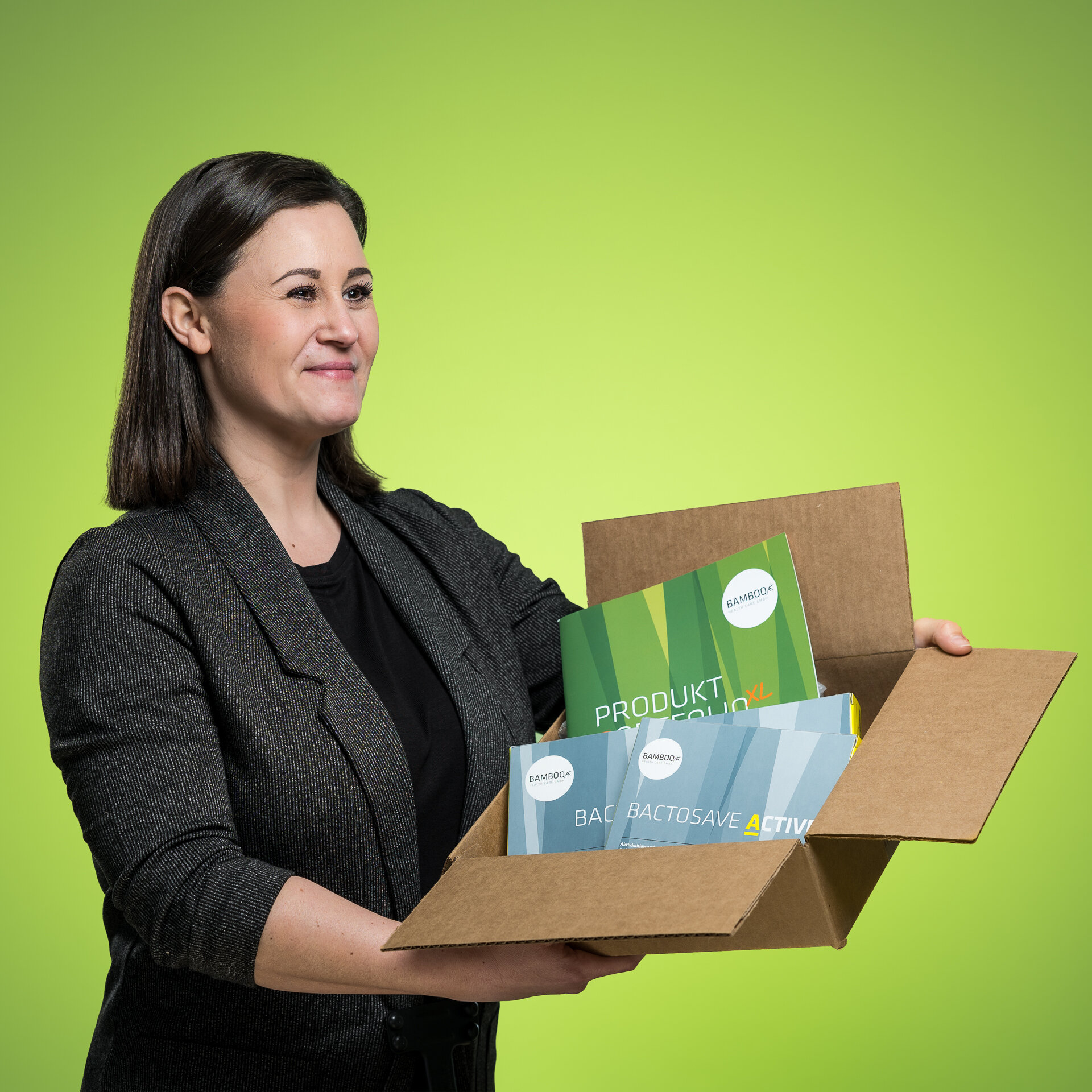 Elisa Capri hält einen offenen Karton, in dem sich Eigenprodukte und Flyer der Firma Bamboo Health Care GmbH befinden. | © Bamboo Health Care GmbH